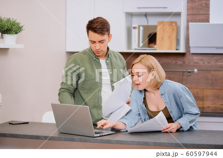 caucasian young spouses sitting with laptop and documents at home caucasian young spouses sitting with laptop and documents at home 60597944