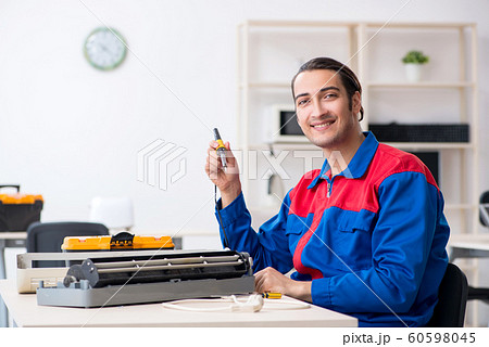 Young repairman repairing air-conditioner at warranty center 60598045