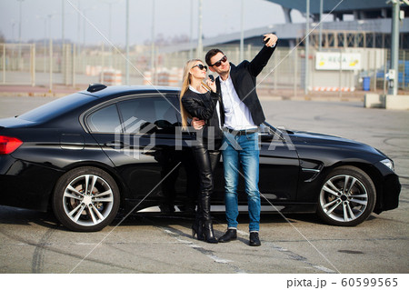 Beautiful couple is holding a key of their new car, looking at camera and smiling Beautiful couple is holding a key of their new car, looking at camera and smiling 60599565
