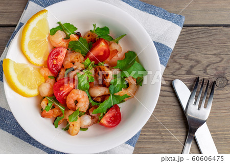 Fresh homemade salad of shrimp, arugula and tomato in a white plate on a wooden table, top view, flat lay, close up Fresh homemade salad of shrimp, arugula and tomato in a white plate on a wooden table, top view, flat lay, close up 60606475