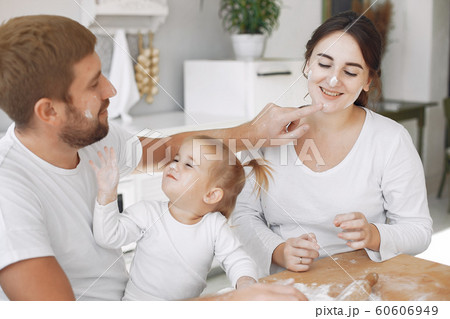 Family sitting in a kitchen and cook the dough for cookies Family sitting in a kitchen and cook the dough for cookies 60606949