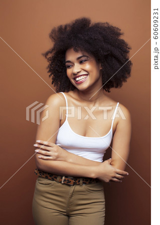 pretty young african american woman with curly hair posing cheerful gesturing on brown background, lifestyle people concept pretty young african american woman with curly hair posing cheerful gesturing on brown background, lifestyle people concept 60609231