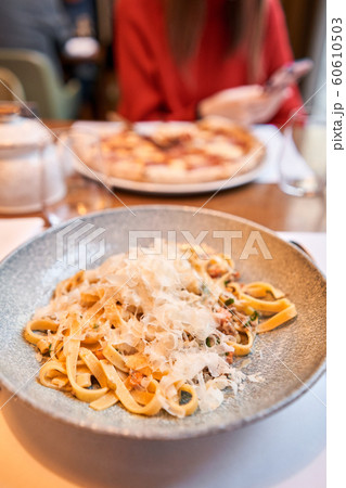Woman eats Italian pasta with duck. Closeup tagliatelle wind it around a fork with a spoon. Parmesan cheese Woman eats Italian pasta with duck. Closeup tagliatelle wind it around a fork with a spoon. Parmesan cheese 60610503