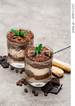 Classic tiramisu dessert in a glass cup, savoiardi cookies and pieces of chocolate on concrete background 60611107