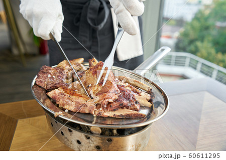 The waiter is butchering with a knife. Various grilled meat set. Barbecue restaurant menu, a series of photos of different meats. 60611295