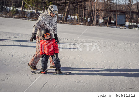Dad teaches son snowboarding. Activities for children in winter. Children's winter sport. Lifestyle Dad teaches son snowboarding. Activities for children in winter. Children's winter sport. Lifestyle 60611312