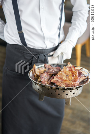 The waiter is holding a plate Various grilled meat set. Barbecue restaurant menu, a series of photos of different meats. The waiter is holding a plate Various grilled meat set. Barbecue restaurant menu, a series of photos of different meats. 60611313