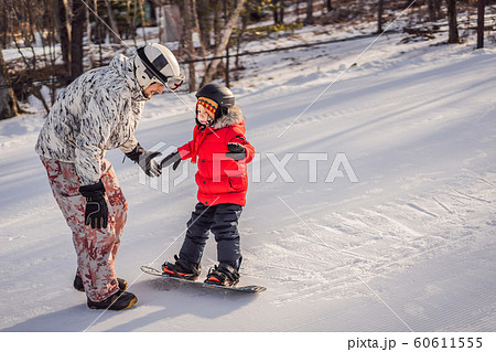 Dad teaches son snowboarding. Activities for children in winter. Children's winter sport. Lifestyle Dad teaches son snowboarding. Activities for children in winter. Children's winter sport. Lifestyle 60611555