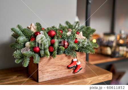 Small arrangement of fresh spruce in a rustic wooden box. Christmas mood. Bokeh of Garland, lamps lights on background. 60611852