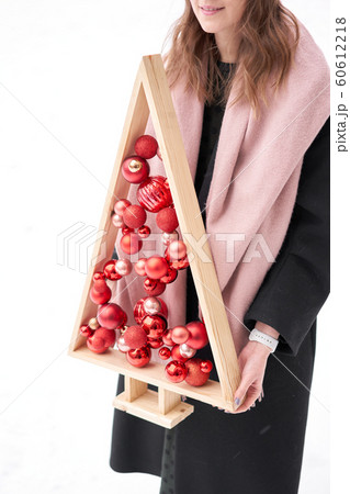 Alternative wooden christmas tree in womans hands . A handmade Christmas tree and red christmas balls. Alternative wooden christmas tree in womans hands . A handmade Christmas tree and red christmas balls. 60612218