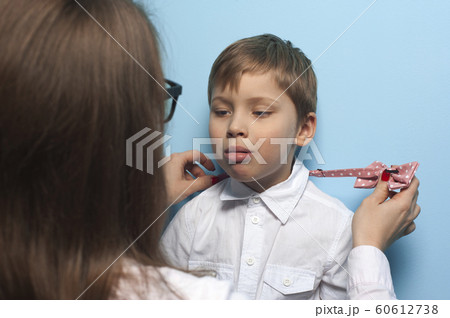 Mom puts her son a bow tie on a white shirt Mom puts her son a bow tie on a white shirt 60612738