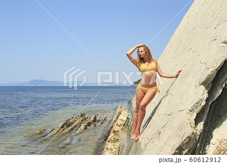Beautiful blonde posing leaning against rock near 60612912