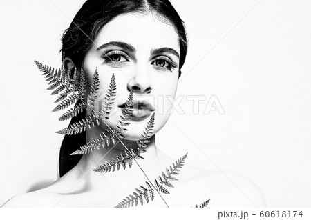 Portrait of an adult brunette woman on a white background with green fern Portrait of an adult brunette woman on a white background with green fern 60618174