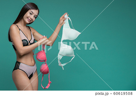 Red and beige bra in brunette woman hands. 60619508