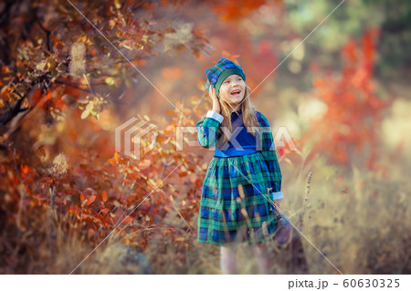 Baby girl dressed in the French style on the background of bright yellow leaves in autumn forest 60630325
