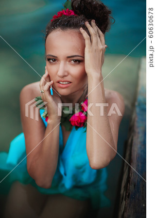 Female model in blue dress and stage makeup posing in water Female model in blue dress and stage makeup posing in water 60630678