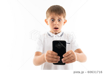 surprised boy looks at the phone on a white background surprised boy looks at the phone on a white background 60631716
