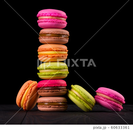 Heap of french colorful macaroons on wooden table isolated on black Heap of french colorful macaroons on wooden table isolated on black 60633361