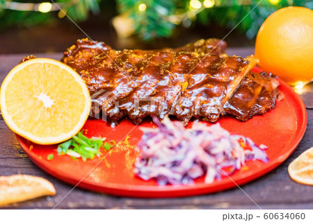 Close up roasted pork ribs in orange sauce served with lemon and vegetables Close up roasted pork ribs in orange sauce served with lemon and vegetables 60634060