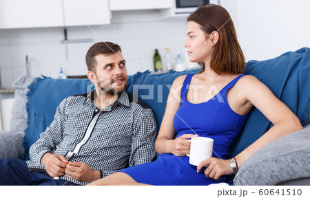 Happy young family couple sitting at sofa and drinking tea in home Happy young family couple sitting at sofa and drinking tea in home 60641510