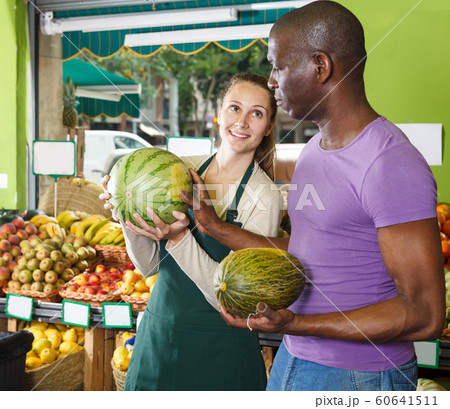 Seller and young client holding watermelon Seller and young client holding watermelon 60641511