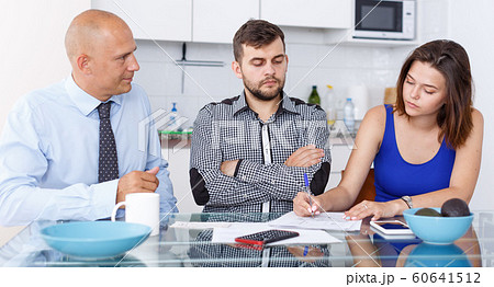 Upset young man and wife signing agreement papers with social worker Upset young man and wife signing agreement papers with social worker 60641512