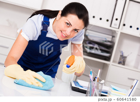 Young and smiling woman in gloves cleaning table Young and smiling woman in gloves cleaning table 60641580