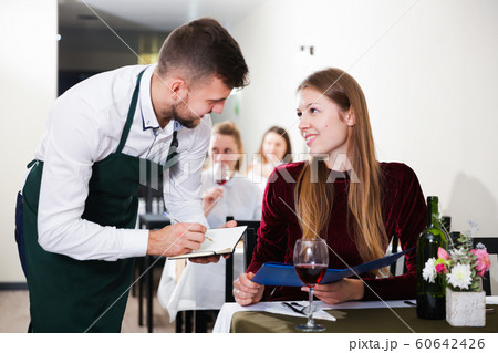 Cheerful woman is giving order to male waiter in luxury restaurante Cheerful woman is giving order to male waiter in luxury restaurante 60642426