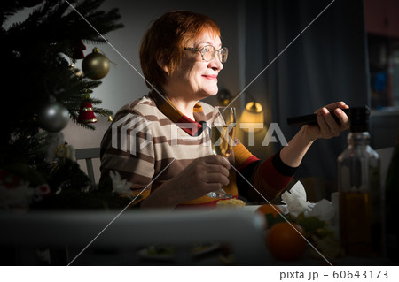 Senior woman with remote control in hand watching TV on New Year night 60643173