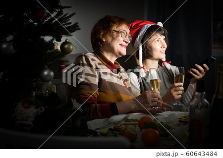 Happy mother and daughter drink champagne and watch TV on Christmas night 60643484