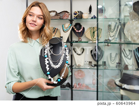 Girl showing pearl necklace on stand Girl showing pearl necklace on stand 60643964