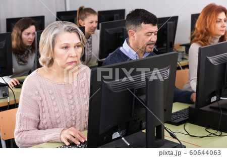 Young and older businesswomen and businessmen in open plan office Young and older businesswomen and businessmen in open plan office 60644063