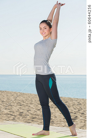 Beautiful woman training on beach by sea 60644256