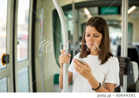 Female using mobile phone in tram Female using mobile phone in tram 60644391