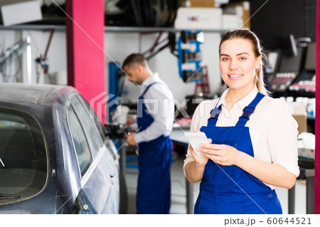 Girl mechanic taking notes on notebook Girl mechanic taking notes on notebook 60644521