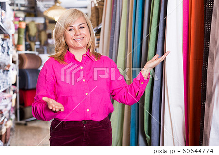 Positive mature female seller offering curtain in store 60644774