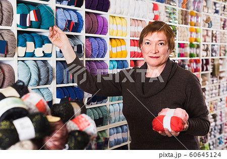 Female is buying colorful yarn for their hobby 60645124