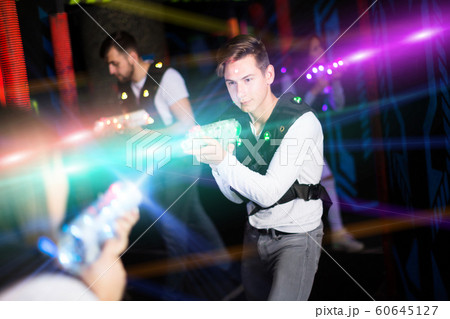 Excited guy laser tag player in bright beams 60645127