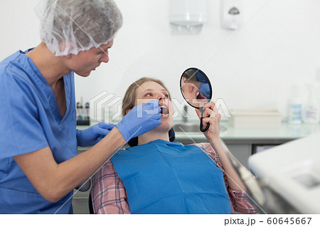 Dentist male in uniform is examinating of female in dental clinic 60645667
