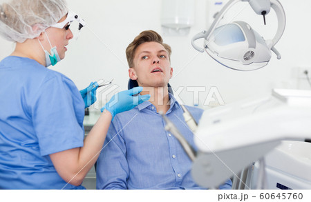 Patient showing dentist the problem in the mirror at the dental clinic 60645760