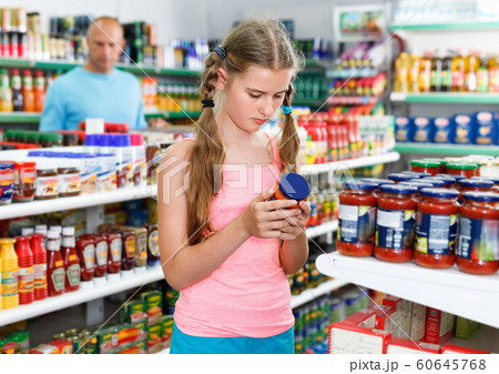 Tween girl choosing and buying food products at grocery shop Tween girl choosing and buying food products at grocery shop 60645768