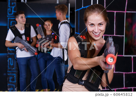 Smiling girl with laser pistol during enjoying laser tag game with her friends Smiling girl with laser pistol during enjoying laser tag game with her friends 60645812