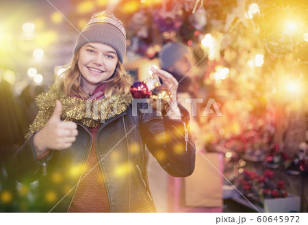 Smiling girl choosing decorations at Christmas market Smiling girl choosing decorations at Christmas market 60645972