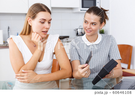 Young happy girl showing new smartphone from box to woman friend Young happy girl showing new smartphone from box to woman friend 60646108
