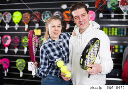 Positive couple choosing padel racket and balls 60646472