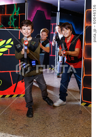 Emotional teen boy with laser pistol playing laser tag with friends on dark labyrinth Emotional teen boy with laser pistol playing laser tag with friends on dark labyrinth 60646556