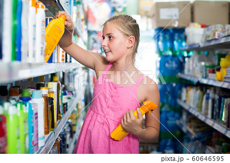 teenager girl choosing bottles of sun protection indoors 60646595