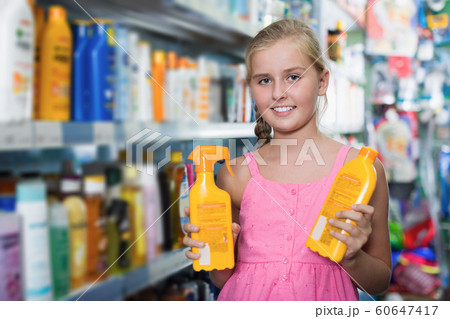 Young girl holding spray and lotion of sun protection 60647417