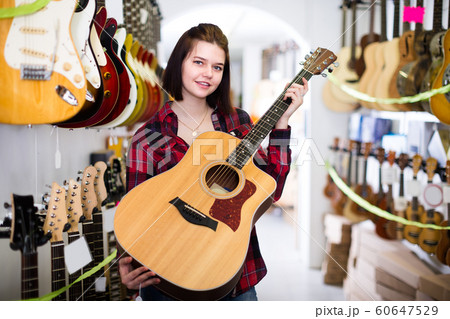 Girl 15-21 years old is deciding on acoustic guitar 60647529