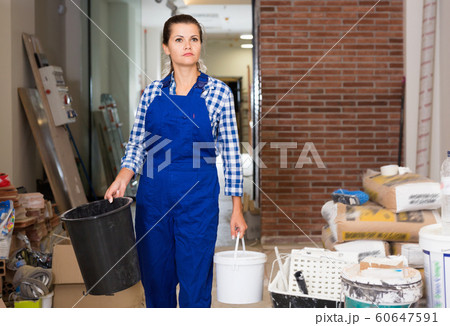 Young female worker holding buckets during doing finishing work in room 60647591